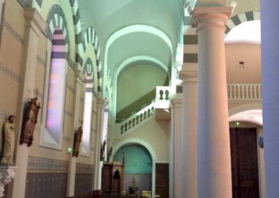 Allée latérale et travées de l’église de saint-étienne-les-houlières, éclairage led discret soulignant arcs, colonnes et mobilier en bois