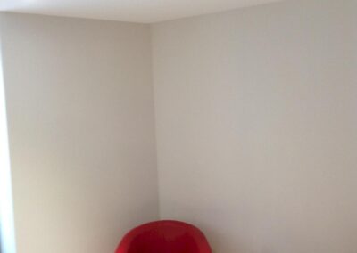 Coin attente du cabinet d’avocats, fauteuil rouge et éclairage homogène par spots encastrés au plafond