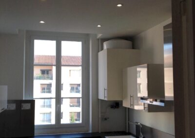 Cuisine rénovée d’un appartement à villefranche-sur-saône, éclairée par des spots encastrés au plafond avec meubles modernes et plans de travail neufs