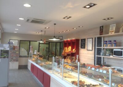 Intérieur du magasin de boulangerie, comptoir vitrine éclairé et plafond équipé de spots après reprise complète de l’installation électrique