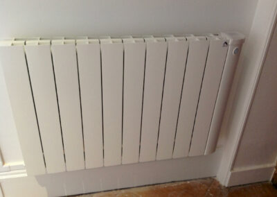 Radiateur électrique à inertie posé dans une pièce de l’appartement, raccordé à la nouvelle installation électrique