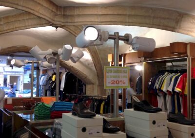 Rayon chaussures et prêt-à-porter sous voûtes de pierre, éclairage led sur rails offrant une lumière homogène dans tout l’espace de vente